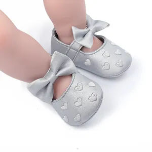 Detailansicht silberner Baby-Prinzessinenschuhe mit Herzstickerei und süßer Schleife