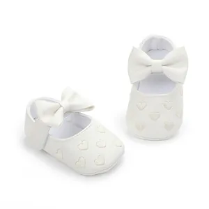 Close-up detail of white baby walking shoes with soft soles and embroidered hearts
