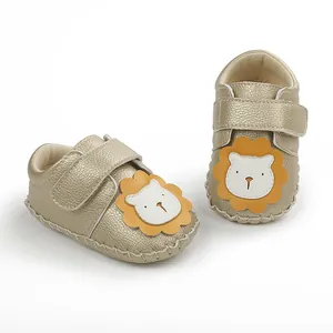 Vue détaillée des chaussures dorées pour bébé avec un joli écusson de lion en dessin animé.