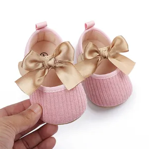 Vista detallada de zapatos de princesa rosa para bebé con lazo de satén dorado