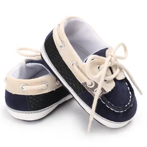Nahaufnahme von dunkelblauen und beigen Baby-Lauflernschuhen mit weißen Schnürsenkeln.