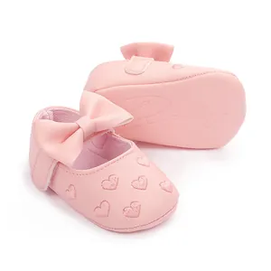 Close-up of pink soft-soled baby pre-walker shoes with heart embroidery and bow
