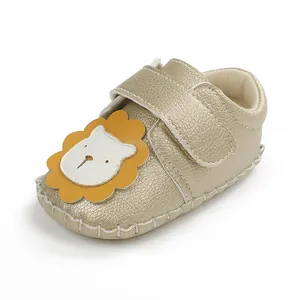 Gros plan sur une chaussure de marche dorée pour bébé avec motif lion et velcro