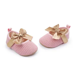 Vista detallada de zapatos de princesa para bebé en rosa con elegantes lazos oro.