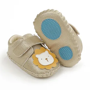 Gros plan de chaussures bébé dorées avec lion de dessin animé et semelle antidérapante