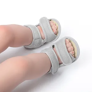 Dichtbij van ademende grijze mesh babysandalen met klittenbandsluiting op babyvoetjes