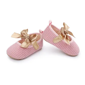 Detalle de zapatos de princesa rosa para bebé con un lazo decorativo de satén dorado