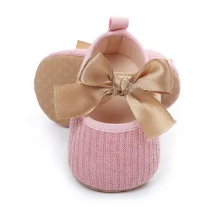 Primer plano de zapatos de princesa para bebé en punto rosa con un gran lazo de raso bronce