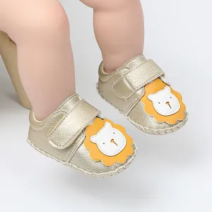 Gros plan sur des chaussures de marche dorées pour bébé avec un motif lion mignon.