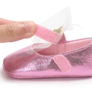 Detail eines rosa Metallic-Babyschuhs mit Klettverschluss und Netzschleife