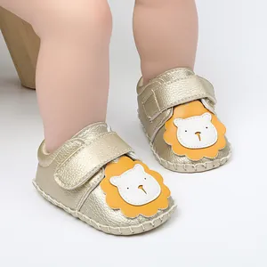Primer plano de zapatos dorados para bebé con diseño de león y cierre de velcro