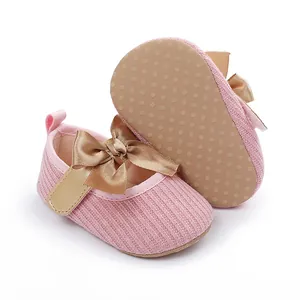 Vista detallada de zapatos de princesa rosas para bebé con lazo dorado y suela suave.