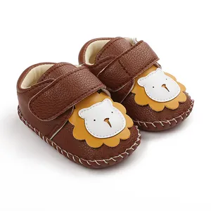 Détail de chaussures de marche pour bébé en cuir marron avec un joli patch de lion.