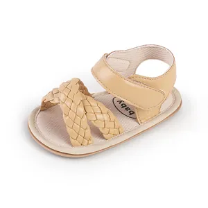 Close-up of woven crossover straps on a beige infant walking sandal with velcro strap