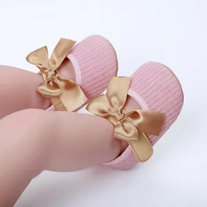Primer plano de zapatos de punto rosa para bebé con elegantes lazos dorados de satén