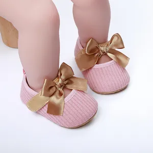 Primer plano detallado de zapatos Mary Jane rosa para bebé con un gran lazo dorado