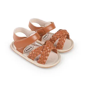 Close-up detail of brown woven straps on baby girl walking sandals for the summer season.