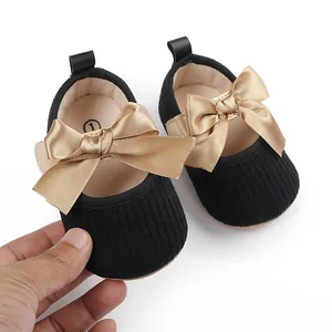 Primer plano detallado de zapatos para bebé niña con un lazo de raso dorado noble