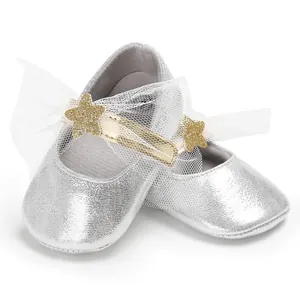 Detailaufnahme silberner Baby-Prinzessinenschuhe mit goldenem Stern und Netzschleife.