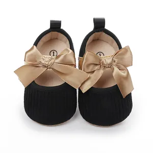 Detalle de zapatos negros para bebé con elegantes lazos de satén dorado