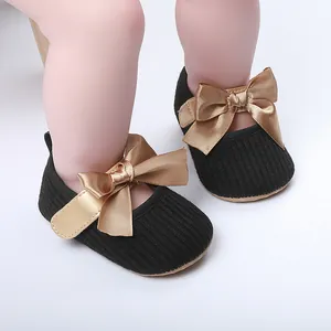 Primer plano de zapatos de bebé negros acanalados con elegantes lazos de raso dorado