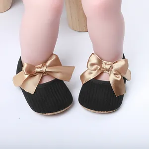 Detalle de zapatos de princesa para bebé negros con elegantes lazos de satén dorado