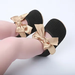 Detalle de zapatos de princesa para bebé en tejido de canalé negro con grandes lazos
