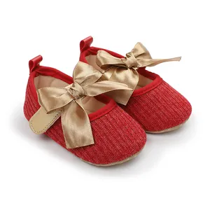 Primer plano de zapatos de princesa para bebé de punto rojo con grandes lazos de satén dorado