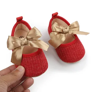 Primer plano de zapatos de princesa rojos para bebé con detalle de lazo dorado