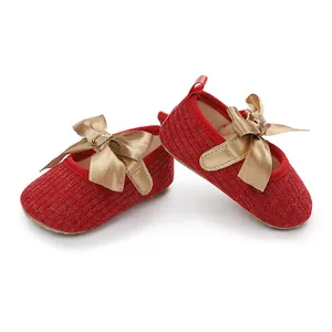 Vista detallada de zapatos de princesa para bebé en punto rojo con un gran lazo dorado