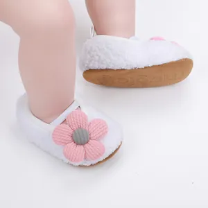 Nahaufnahme von weißen flauschigen Babyschuhen mit rosa Blume und weicher Sohle.