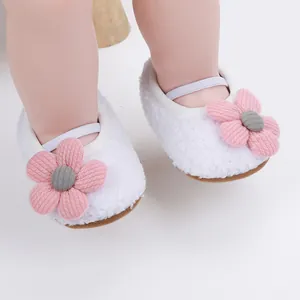 Nahaufnahme von weißen Plüsch-Babyschuhen mit rosa Blumendekoration im Detail