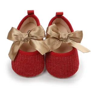 Primer plano de zapatos rojos de princesa para bebé con un gran lazo dorado de satén