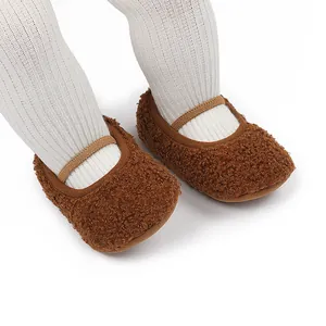 Dichtbij van bruine pluizige babyschoentjes met elastische band en witte geribbelde panty