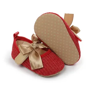 Detalle de zapatos rojos de princesa para bebé con lazo dorado grande y suela antideslizante