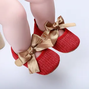 Primer plano de zapatos de princesa para bebé en punto rojo con lazos dorados
