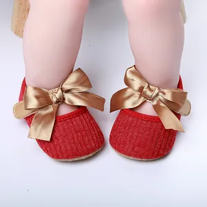 Zapatos de princesa rojos para bebé con grandes lazos de satén dorado.
