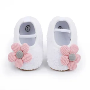 Draufsicht auf weiche weiße Baby-Lernlaufschuhe mit hübschen rosa gestrickten Blumen