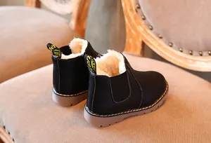 Primer plano de botas Martin negras para niños con forro cálido de piel sintética blanca