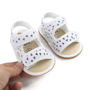 Detailed view of white canvas baby sandals featuring black triangle prints and soft soles