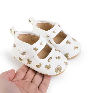 Detail view of baby walking shoes with heart pattern held in hand for scale
