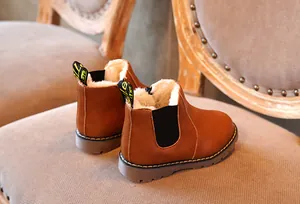 Primer plano de botines marrones para niños con forro polar cálido en silla vintage