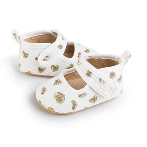 Detailed view of baby pre-walker shoes featuring gold heart patterns and velcro straps.