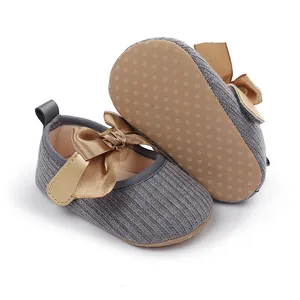Vista detallada de zapatos de punto para bebé con suela antideslizante y lazo dorado