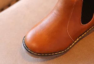Primer plano de la textura de cuero sintético marrón y las costuras de las botas infantiles