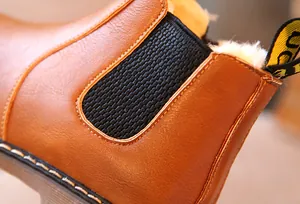 Primer plano de botines Chelsea marrones para niños con forro de felpa y elástico lateral.
