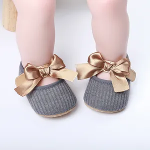 Primer plano de zapatos de princesa para bebé grises con lazo de satén bronce