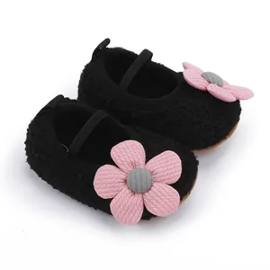 Nahaufnahme von weichen, schwarzen Baby-Lauflernschuhen mit einer süßen rosa Blume