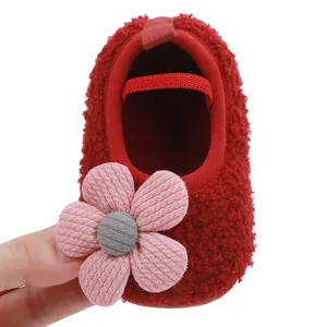 Macro view of red plush baby walking shoe featuring a soft pink fabric flower detail