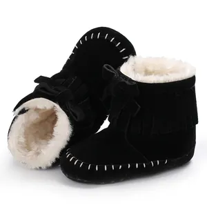 Close-up of black baby fringe boots with warm white faux fur lining and cute bow.